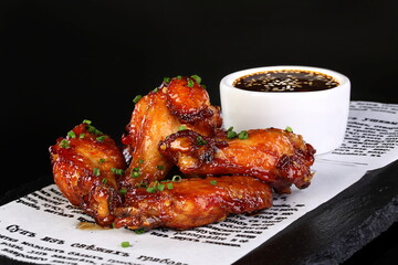 Chicken legs in teriyaki sauce on black background