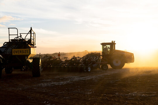 Tractor and air seeder planting wheat at sunset