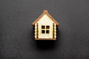 Obraz na płótnie Canvas Miniature wooden toy house on a black background. Real estate object. Concept of buying an apartment, house, real estate. Copy space. Flat lay.