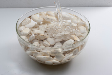 Bol de alubias  crudas llena de agua, para elaborar platos. Cannellini beans soaking in water