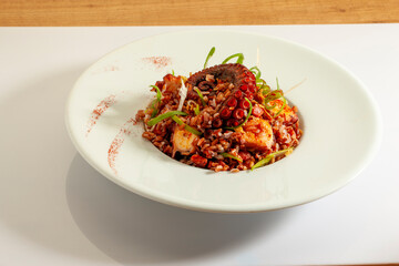 Arroz con pulpo sobre mesa con mantel. Rice with octopus on a table with a tablecloth.