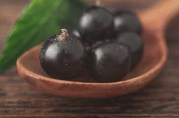 Currant berries on a wooden spoon lying on a textured table. Macro photo.