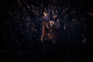 Scary halloween witch standing over spooky dark forest with tree, leaves and vine, Halloween mystery concept