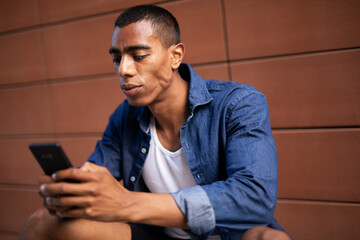 Portrait of happy african-american man with skateboard. Young handsome man using the phone