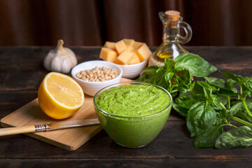 Pesto sauce in a glass bowl and ingredients for making basil sauce at home