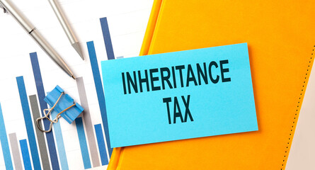 INHERITANCE TAX text on sticker on the yellow notebook with chart and pen