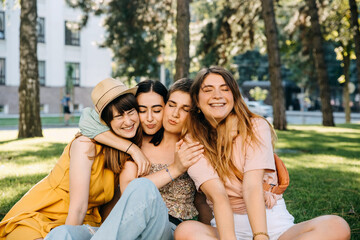 Group of four women, best friends outdoors, hugging and laughing.