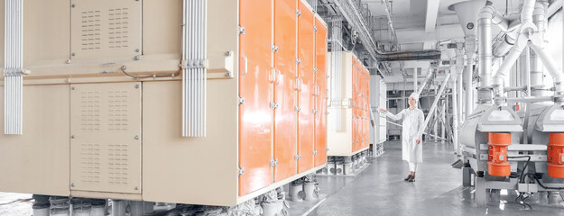 Operator checks operation of vibrating machine for sifting flour from wheat and cereals, industry automatic modern mill