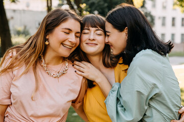 Closeup portraits of three young women hugging and smiling.