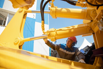 Machinery tractor mechanic checks hydraulic hose system equipment on excavator