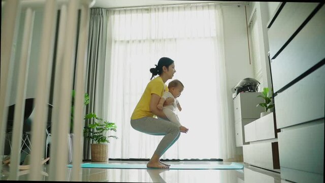 Asian Young mother doing physical yoga exercise with her baby boy at living room.