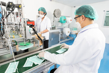 Fototapeta na wymiar male factory worker are producing medical face masks and checking of quality from machine