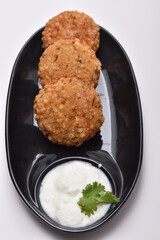 sabudana wada or shabudana vada with curd in black dish with white background