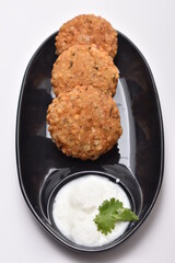 sabudana wada or shabudana vada with curd in black dish with white background and coriander