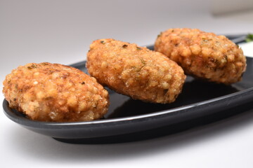 Close up shot of sabudana wada or shabudana vada in black dish with white background