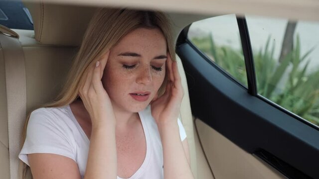 Stressed young woman with freckles suffering from muscles tension, having painful head feelings overwork or sedentary working lifestyle. Tired business woman stressed in car.