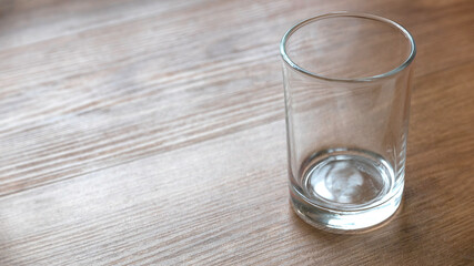 An empty glass on a wooden background with copy space.