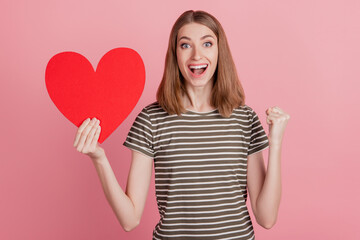 Portrait of crazy excited lady hold red paper heart celebrate victory on pink background