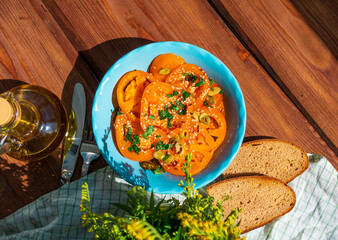 Yellow tomatoes salad with rye bread slices in blue ceramic bowl top view. Ripe fresh colorful vegetables mixed sliced greens with olive oil vinegar pumpkin sesame flax seeds on wooden background.