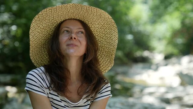 close-up portrait of a cute adult lady relaxing in nature with a big hat on her head