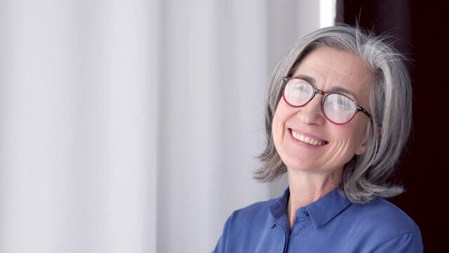Happy adult lady in red eyeglasses smiling, enjoying view from window, good mood