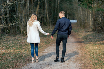Obraz premium Beautiful loving couple going for a walk in a forest in the spring,autumn outdoors sunny day.Rear view.