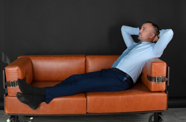 Did the job. A satisfied businessman is resting in the office with his hands behind his head. A...