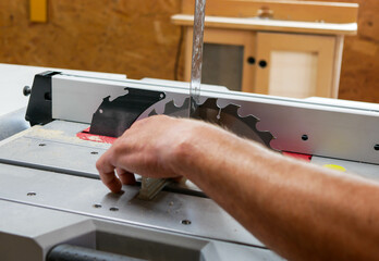 Carpenter adjusting the blade using a right angle square at the table saw, focus on the square.