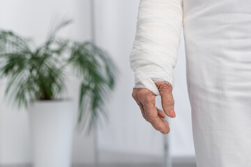 Cropped view of elderly woman with plaster bandage on arm in clinic