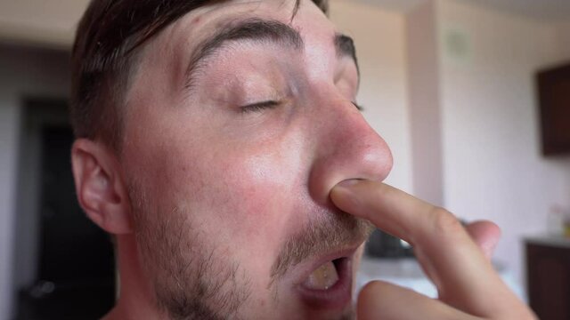 Weird funny Man picking nose, Tastes Boogers Taste Tongue and And Wrinkles Your Face With Comical Stupid Expression. Crazy Carefree Brunette Man Picking Nose With Comical Humorous Expression