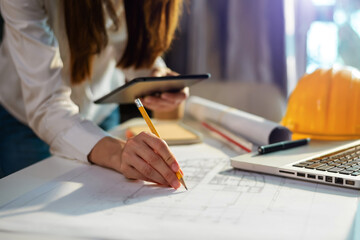 business man hand working and laptop with on on architectural project at construction site