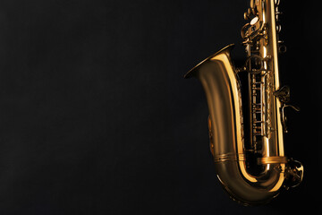 Fototapeta na wymiar Beautiful saxophone on black background, top view. Space for text
