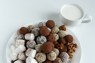 truffles with cocoa, coconut and sesame with chocolate and marshmallows and a cup of fresh milk, delicious dessert
