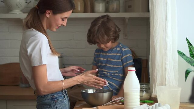 Family cooking in kitchen. Mother son cook together boy looks at sieve in mom hands