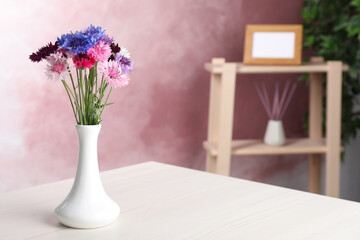 Bouquet of beautiful cornflowers in vase on white wooden table at home. Space for text