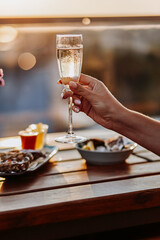 Woman eating fresh oysters and drinking chilled prosecco wine on the summer sunset. Seafood delicacies