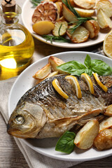 Tasty homemade roasted crucian carp served on wooden table, closeup. River fish