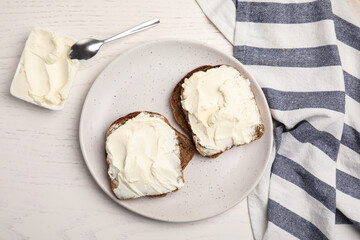 Bread with cream cheese on white wooden table, flat lay