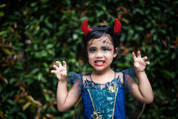 Adorable girl in halloween costume standing against nature background.