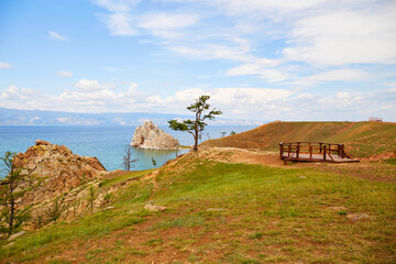 Obraz premium Shamanka Rock and an old larch tree on the island of Olkhon. Beautiful summer landscape of Lake Baikal.