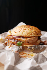  beef burger on a chopping board against black background 