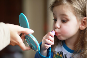 Cute little girl playing with cosmetic at home