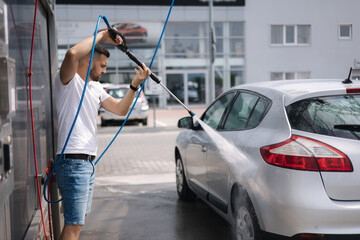 Process of man washing his car in a self-service car wash station