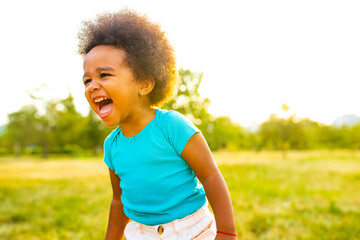 adorable small mixed race girl walking alone in park at sunset time