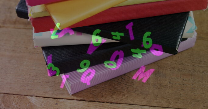 Digital composition of multiple changing alphabets and numbers floating against stack of books on wo