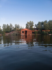 Old, abandoned, collapsed wooden house on the water on the river.