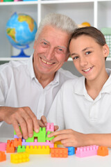 Smiling boy playing with colorful plastic blocks with grandfather