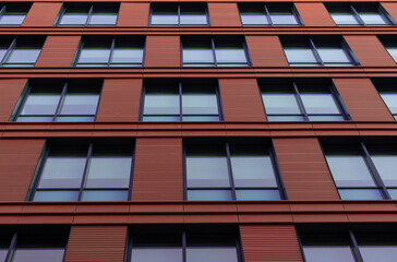 Brick colored wall with big windows. Part of facade modern urban building, bottom-up view.