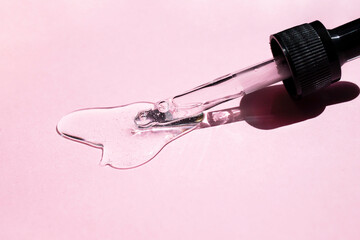 Hyaluronic acid with a dropper on a pink background. Side view.