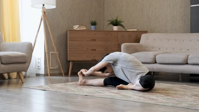 Fit woman high body flexibility stretching her leg to warm up doing aerobics gymnastics exercises at home